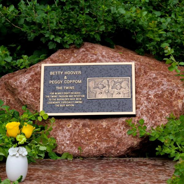 A plaque honoring the late Betty Hoover and her twins sister, Peggy Coppom, sits between "twin" trees planted along the Buff Walk on the east side of Folsom Field. (Photo by Glenn Asakawa/University of Colorado)