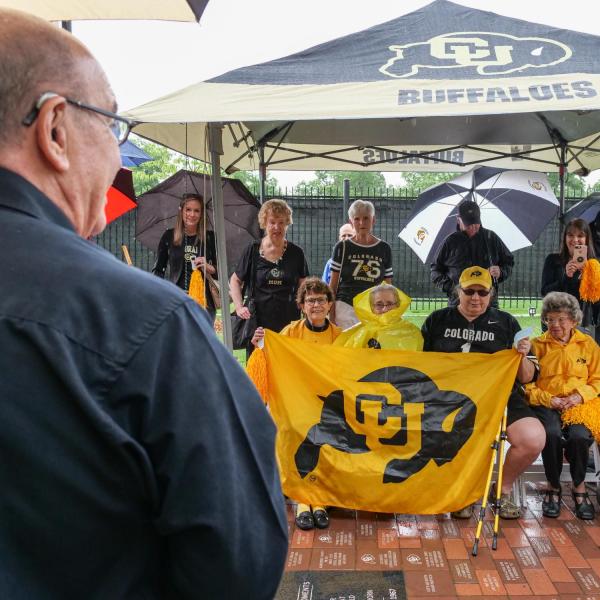 Chancellor Philip DiStefano, left in foreground, Athletic Director Rick George (not visible) and others gathered on June 26 for a tree dedication ceremony honoring CU Buffs super fans Peggy Coppom, seated second from left, and her late sister Betty Hoover. (Photo by Glenn Asakawa/University of Colorado)