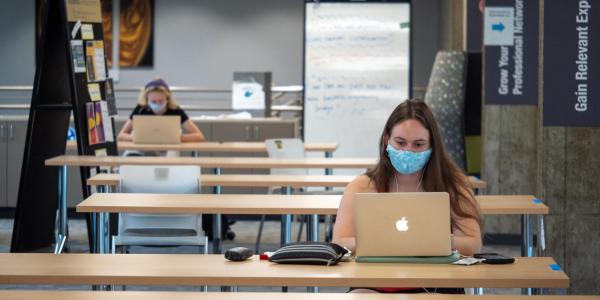 Students in masks studying in the Engineering Lobby. 