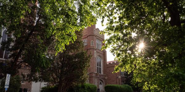 Sun filters through the trees in early morning by Macky Auditorium