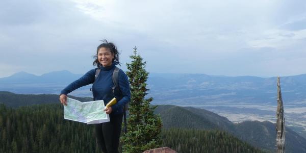 Sabrina Kainz holds up a map while standing on a rocky overlook