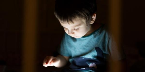 Little boy using tablet device at nighttime