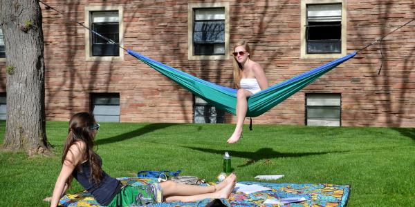 Students lounging on a hammock campus in the summertime