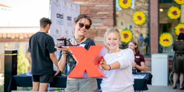 Students hold up a red X, of the TEDx logo, at an involvement fair booth