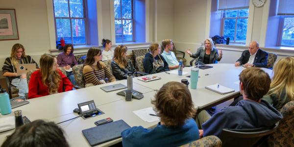 A Community Scholars Program cohort meets at a conference table. 