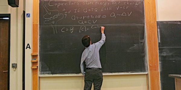 Physics professor writing on a blackboard in the classroom