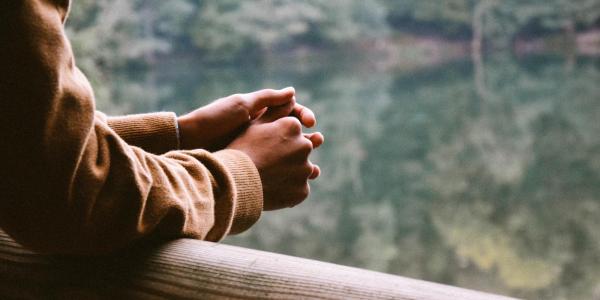 Person holds hands together, looking outside