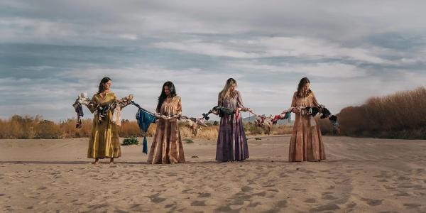 Women in long dresses holding a chain of abandoned belongings near the border