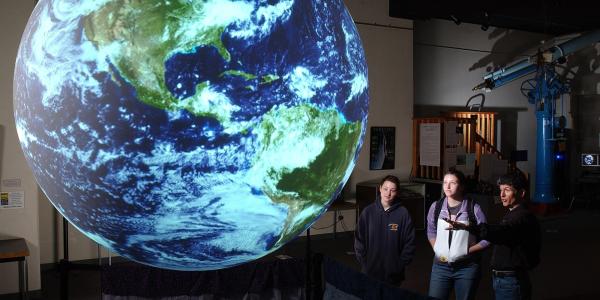 Onlookers observe a giant glowing globe at Fiske Planetarium