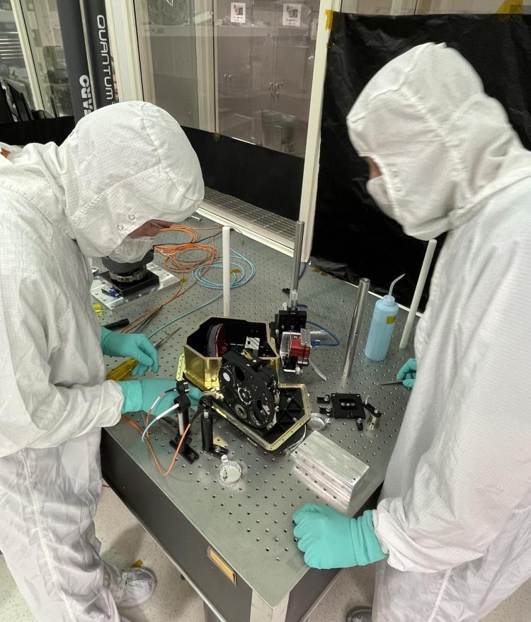 Researchers in a cleanroom work on a space instrument