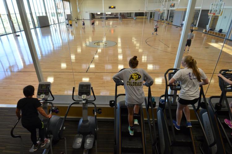 Students on ellipticals and stair climbers overlooking basketball courts at The Rec