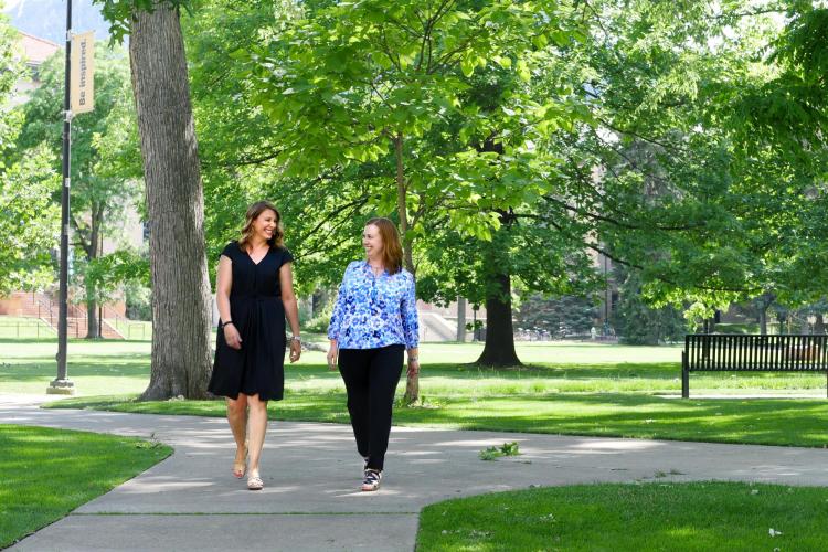 Staff members Alana Davis-Delaria and Eryn Elder walk on campus