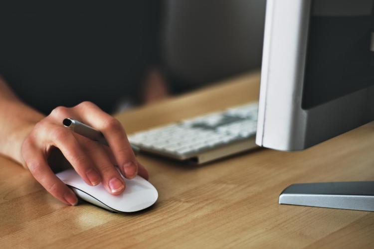 Person moving mouse on Apple computer