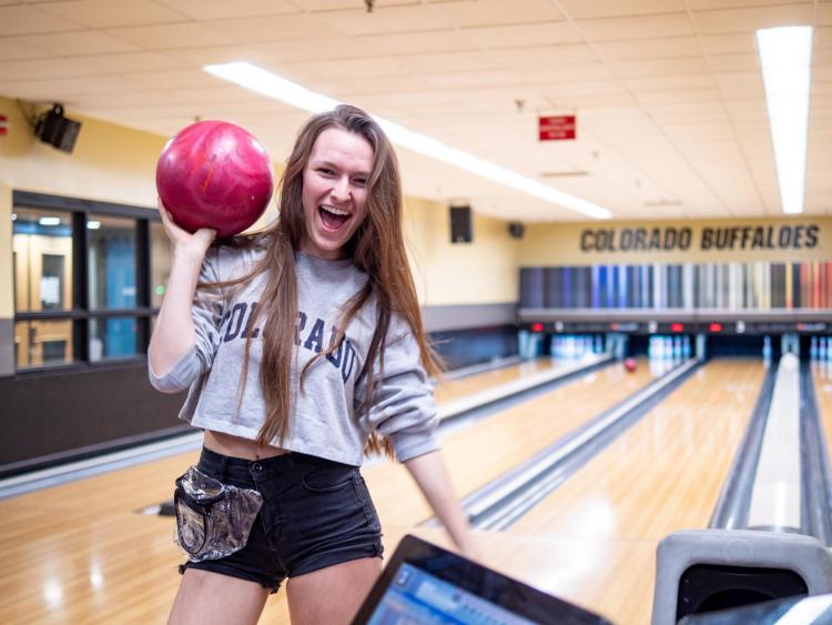 A student poses with a bowling ball at The Connection on campus