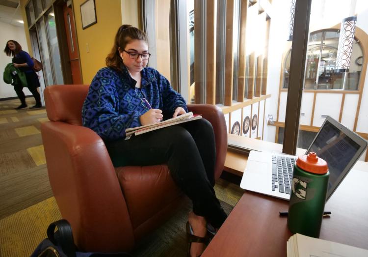 Student writes in notebook with laptop computer nearby