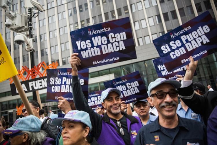 Man holds up DACA sign at apparent rally outdoors