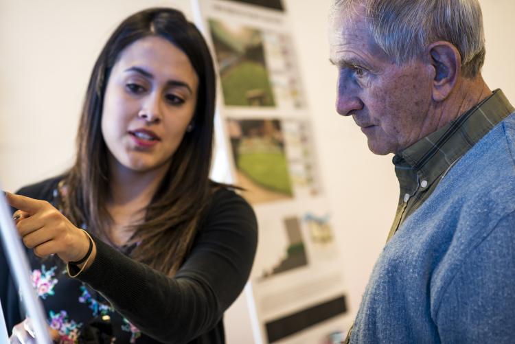 A student discusses a design drawing with a community member.