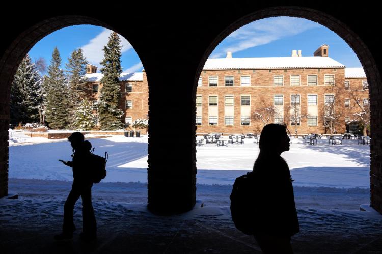 Silhouettes of students walking on campus on a snowy day