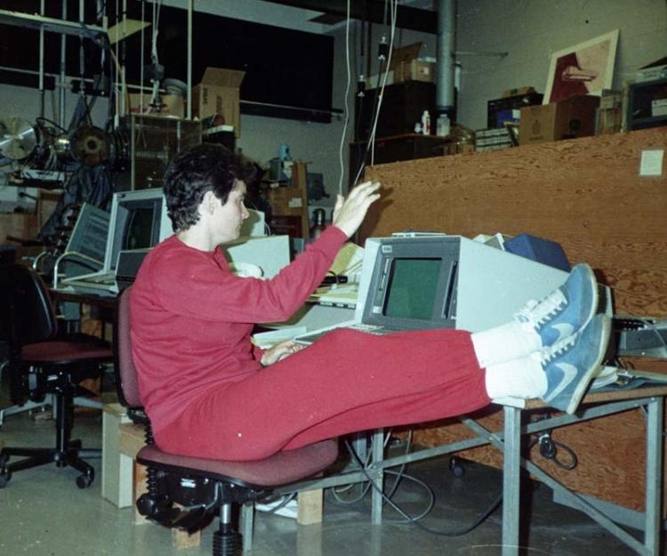 Woman in red track suit puts her feet up while working on a desktop computer