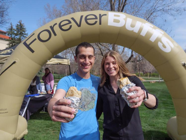 2022 graduating students enjoy free breakfast burritos in front of a Forever Buffs sign