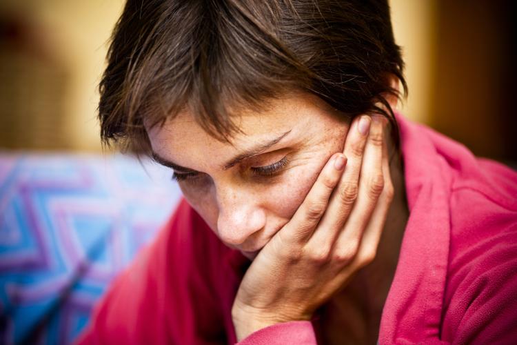 Woman holds head in hand | iStock photo credit to RapidEye