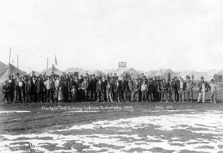 Black and white image of dozens of men gathered in front of tents