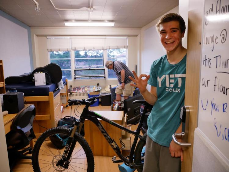 Student moving into dorm room with bicycle in background