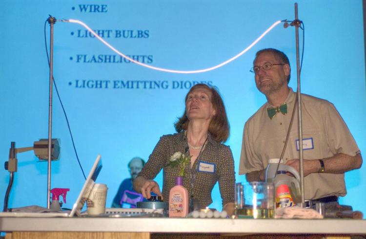 Two faculty members present a electrical light-based experiment.