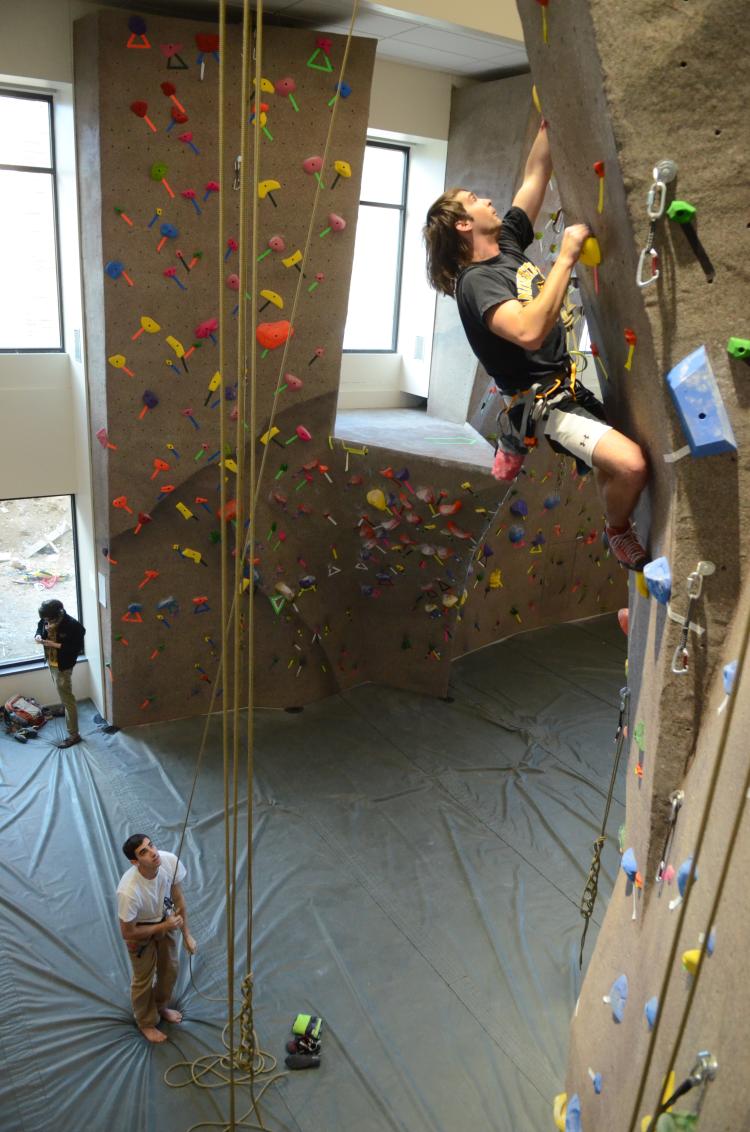 A student climbs on the climbing wall at the Rec Center