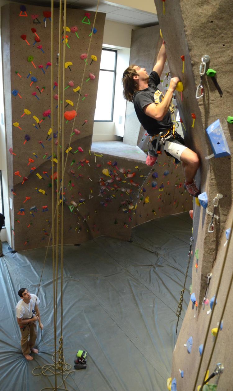 Student climbs up The CU Boulder climbing wall