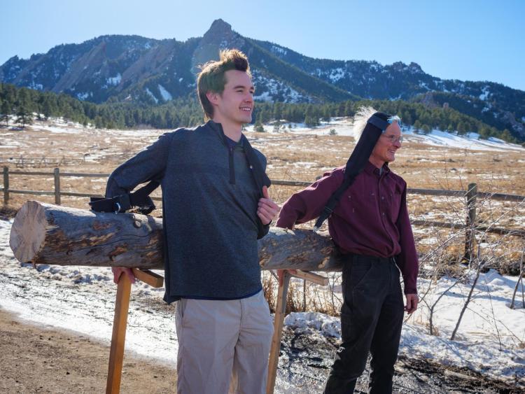 James Wilson and Rodger Kram pose while resting a log they're carrying on sticks