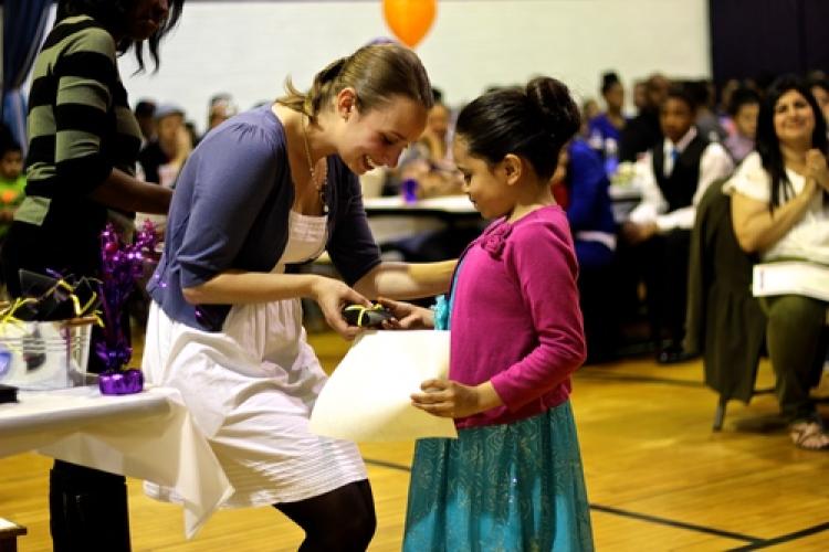 A girl receiving an award during a positive recognition campaign event in Montbello