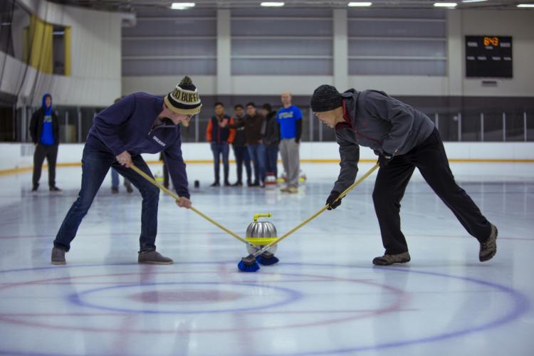 Students curling on the ice rink at The Rec