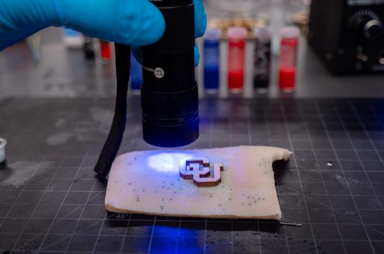 Bruns shines an ultraviolet flashlight on a tech tattoo.