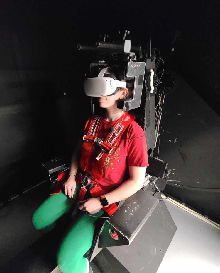 Woman sits strapped into heavy-duty chair wearing a virtual reality headset