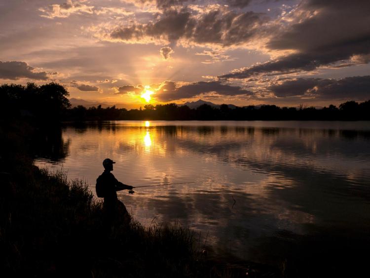 Person fishing on a lake at sunset