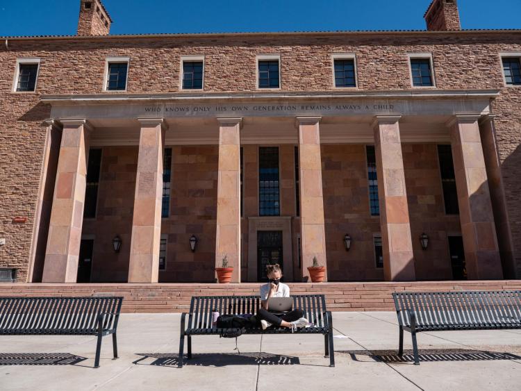 student sitting on a bench at Norlin Quad