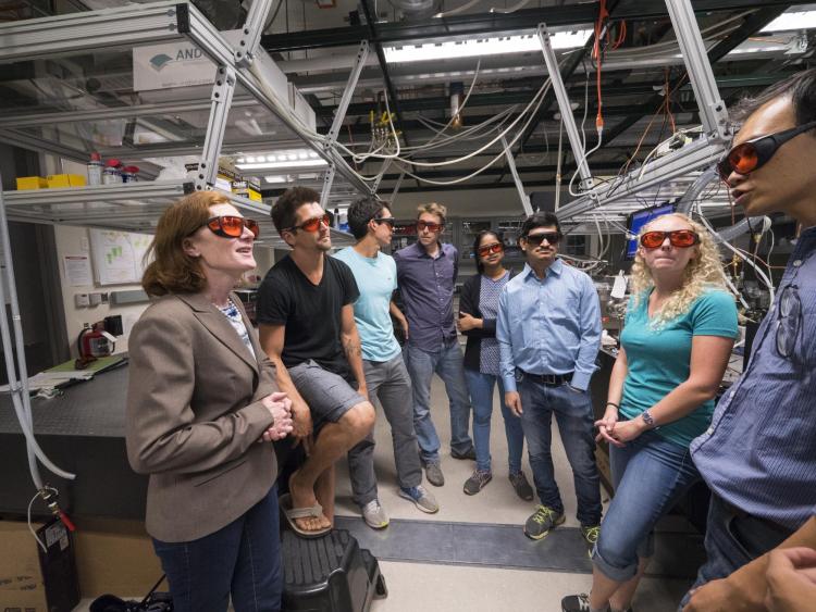 Margaret Murnane, wearing safety goggles, talks to her students in the lab.