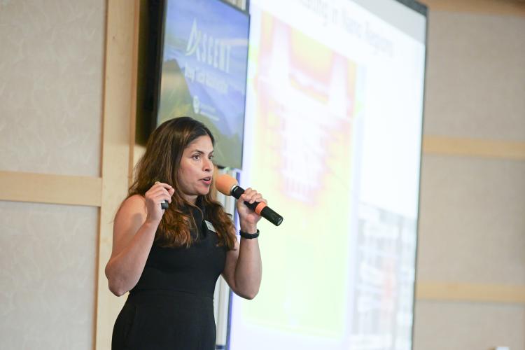 Woman speaking into microphone at a business pitch event