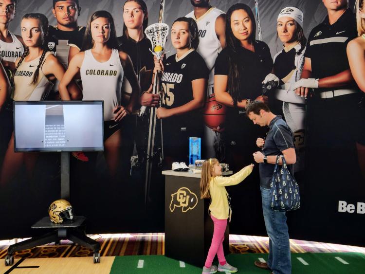 Lily Ritchey, 6, passes along a Buff button to her dad Michael Ritchey (MechEngr'02). Photo by Glenn Asakawa.