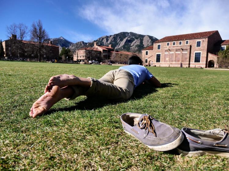 Freshman Zach Ramirez kicks off his shoes while enjoying the warm weather at Farrand Field. Photo by Glenn Asakawa.