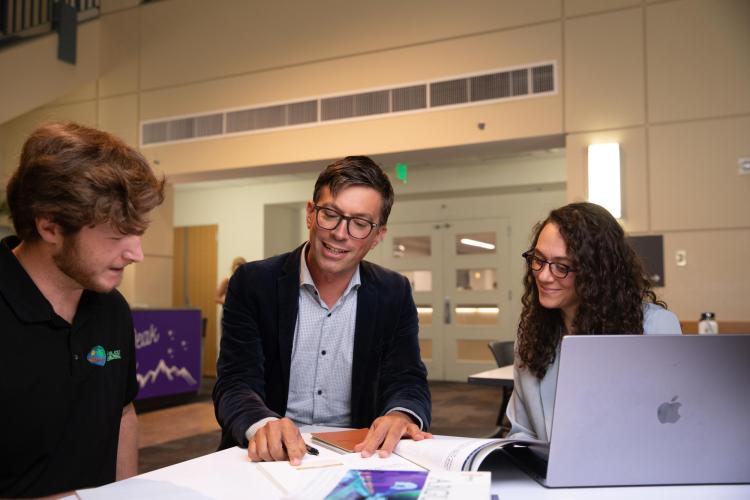 Professor Christophe Spaenjers,speaks with graduate students in the Koelbel building