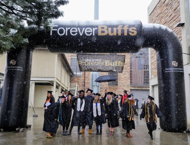 Graduates pose for a photo under a blow-up Forever Buffs arch