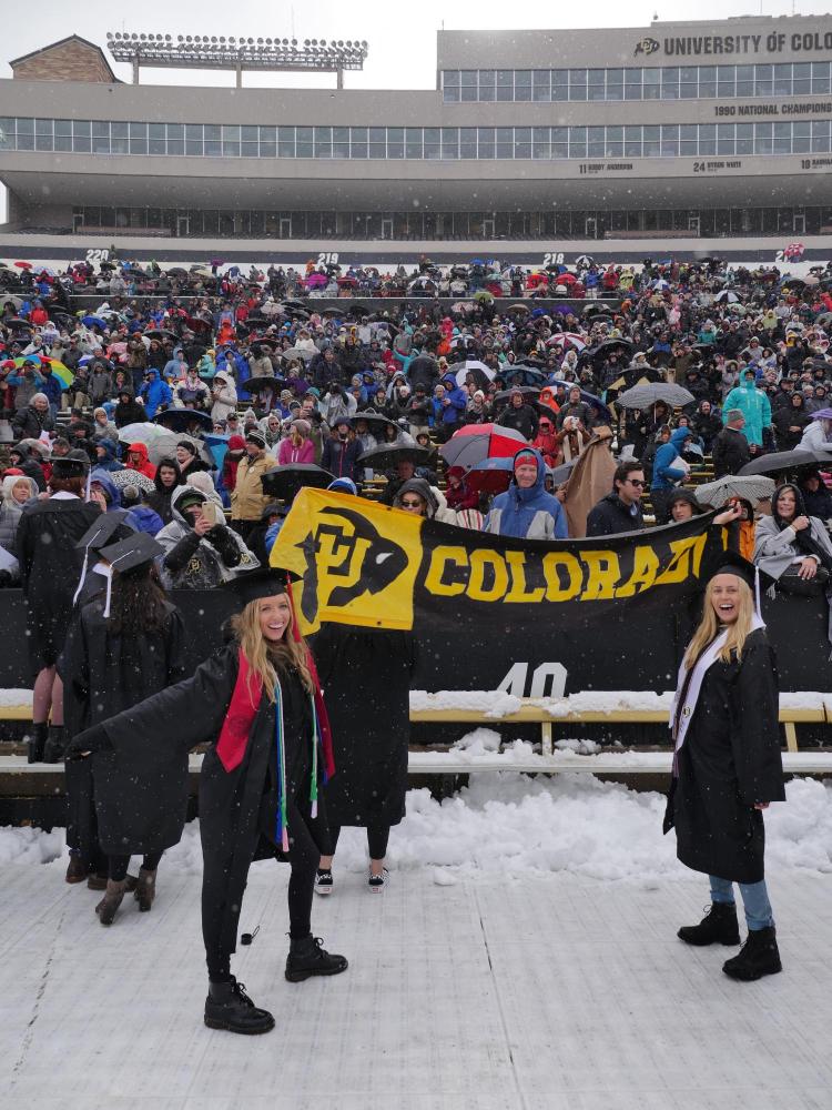 Graduates hold up a black and gold Colorado banner