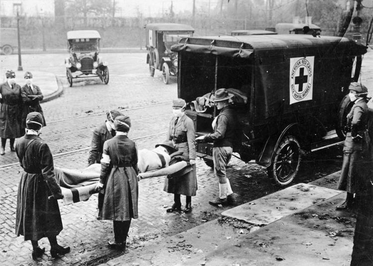 Victims of the 1918 flu loaded into an ambulance by masked workers
