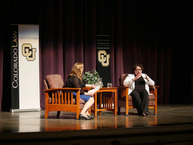 Sonia Sotomayor speaks on the Macky Auditorium stage, seated in a chair with Professor Melissa Hart also seated in a chair to the left of the justice.