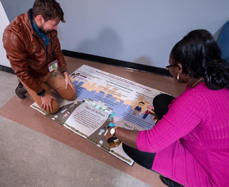 Staff put the finishing touches on a Staff Council-produced poster during the second day of events. Photo by Glenn Asakawa.