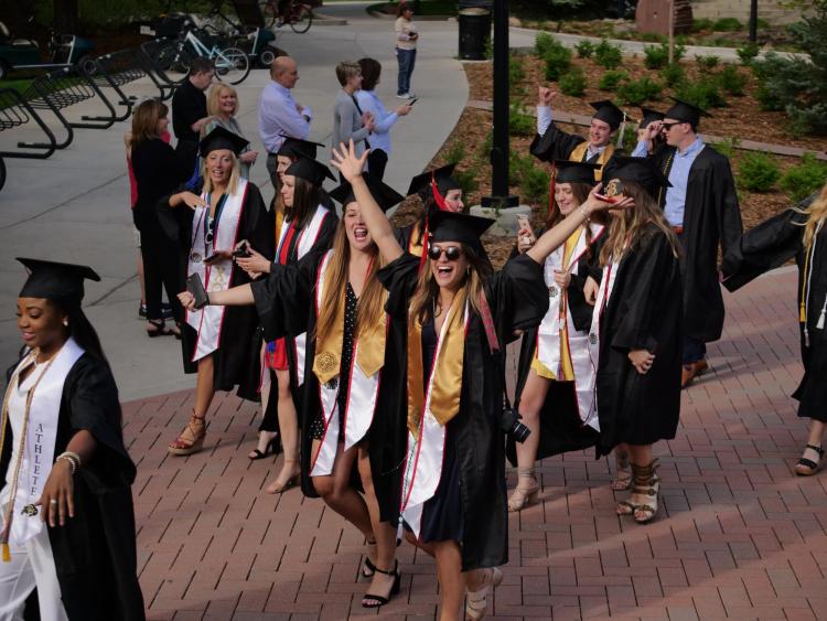 Graduates enjoy the procession from the quad to CU Boulder's 2018 main commencement ceremony at Folsom Field. Photo by Glenn Asakawa.
