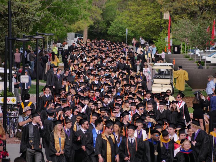Graduates process to the main commencement ceremony at Folsom Field. Photo by Glenn Asakawa.