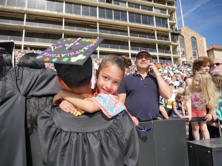 Trevor Jordan, sociology major and minor in anthropology, hugs his daughter Violet, 6, before the ceremony. Photo by Glenn Asakawa.